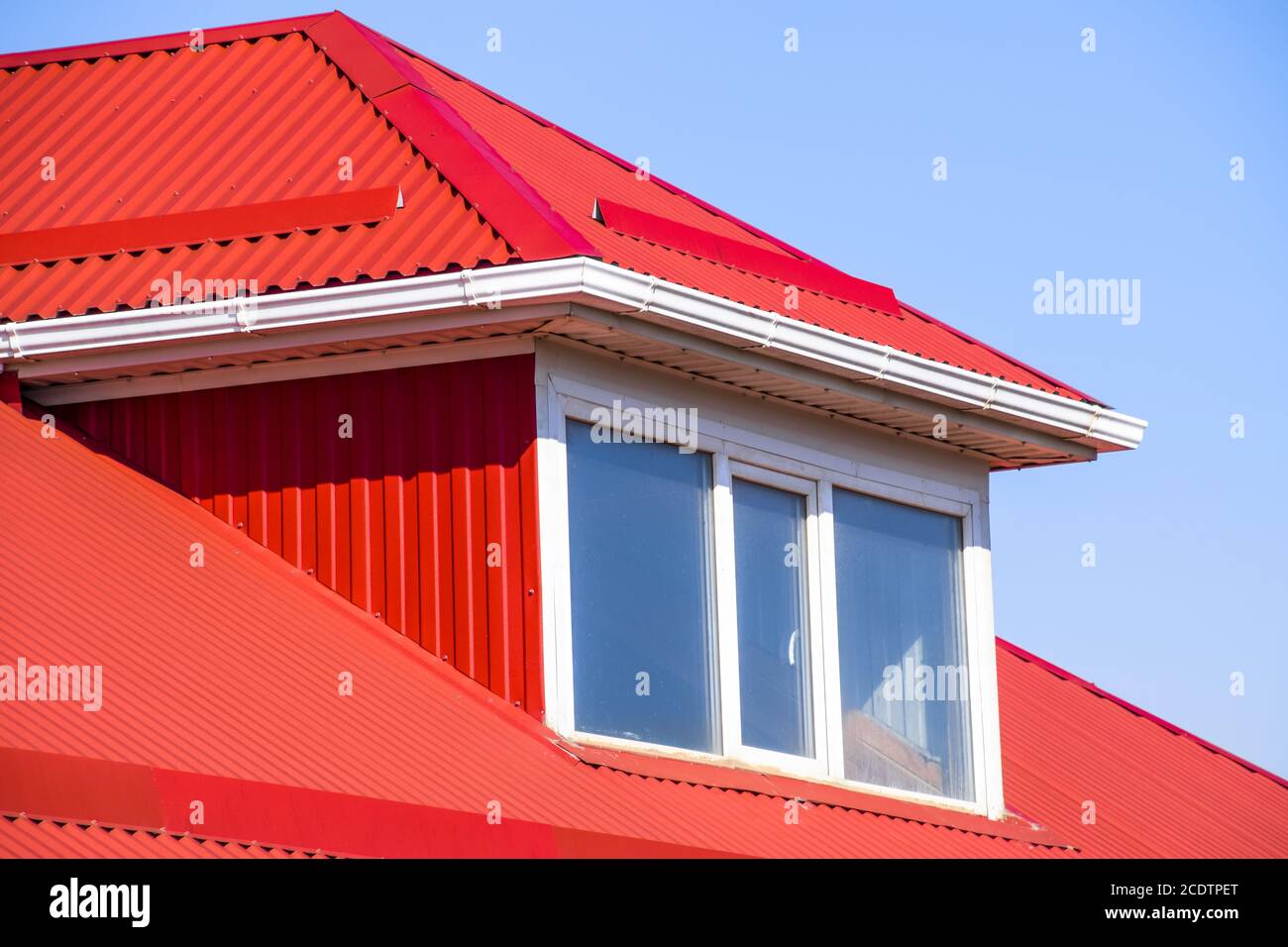 Casa con ventanas de plástico rojo y un techo de chapa ondulada Foto de stock