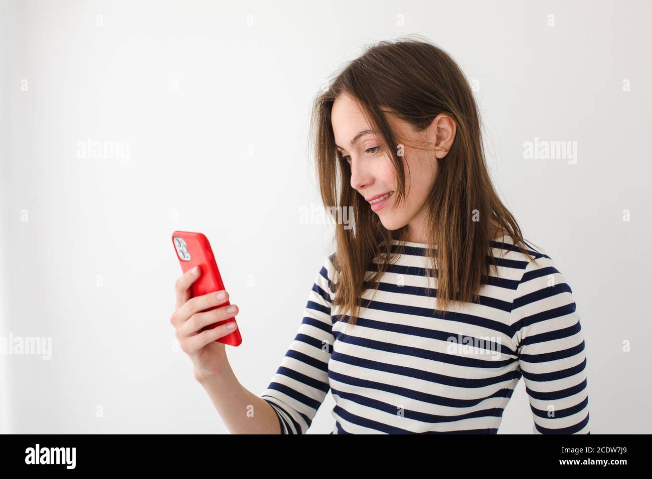 Mujer sonriente navegando smartphone en casa Foto de stock