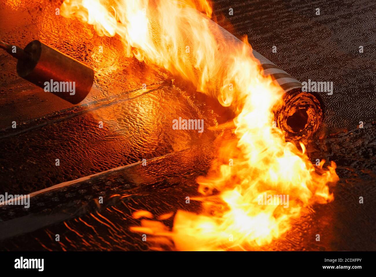 Colocación de revestimientos asfálticos en el rollo con la llama del quemador de cerca. Foto de stock