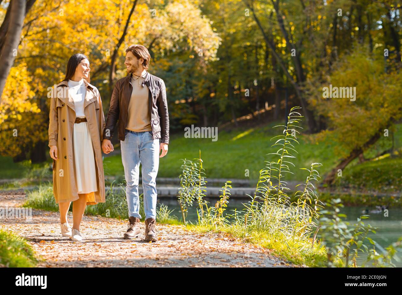 Feliz pareja joven enamorada caminando por el bosque otoñal Foto de stock