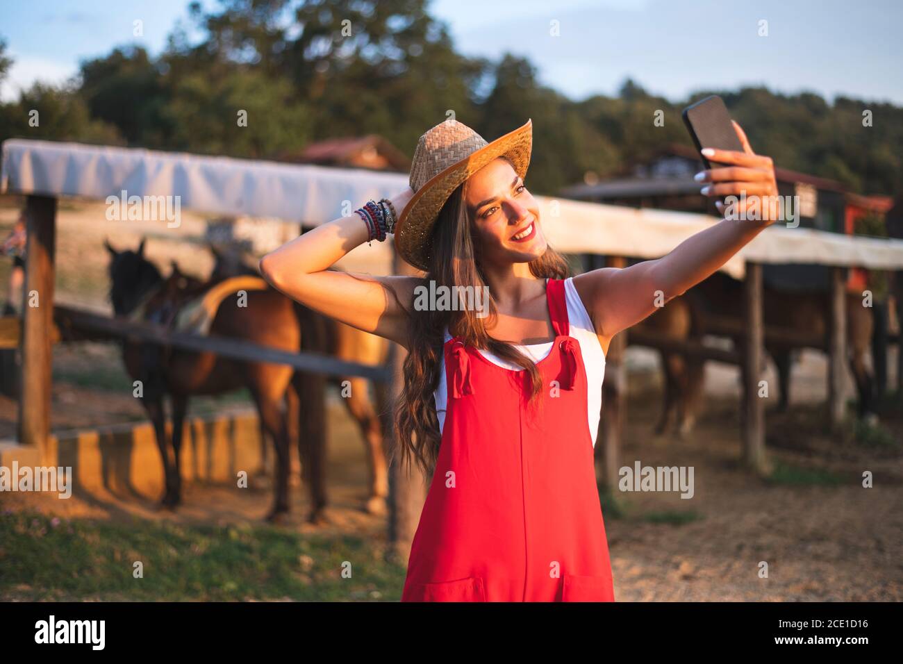 Sonriendo hermosa joven disfrutando en el campo en la Granja de caballos y hacer Selfie. Fotografía del concepto de rancho Foto de stock