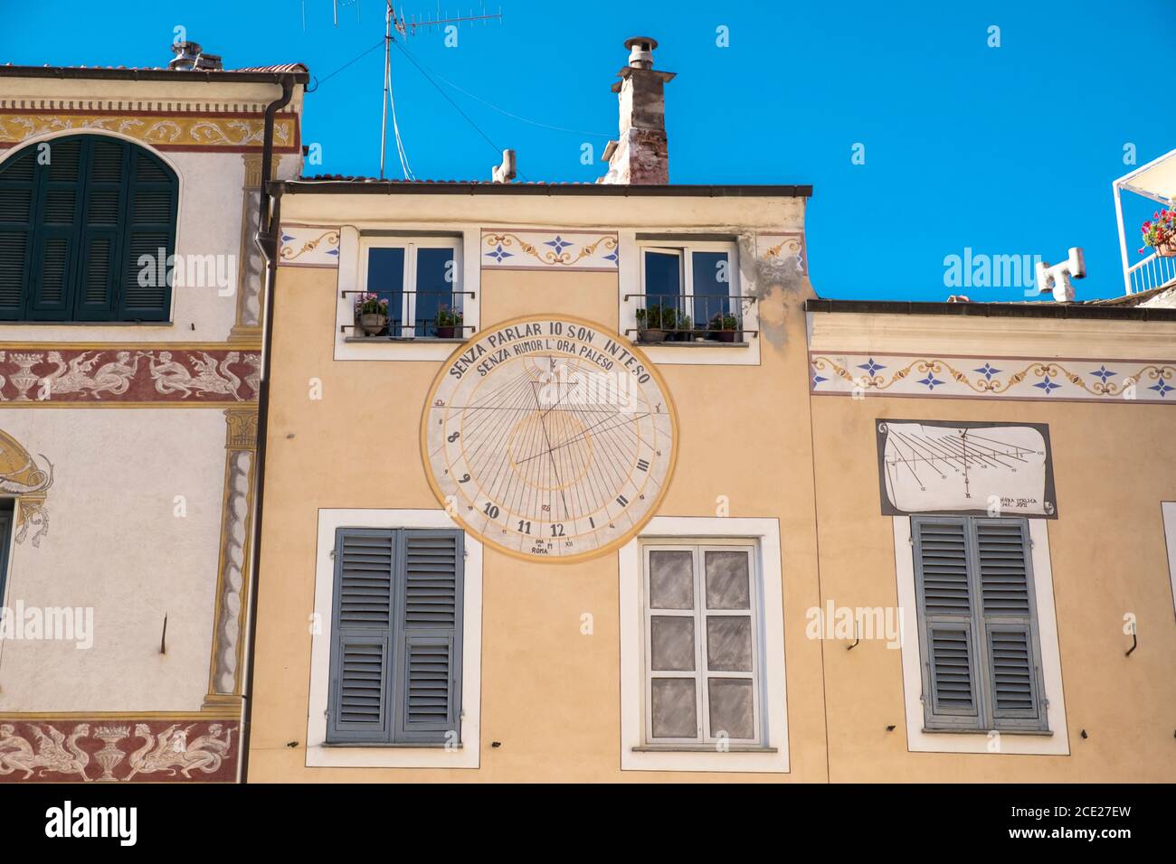 Antiguos edificios amarillos con reloj de sol en el casco antiguo de Finalborgo, Finale Ligure, Liguria, Italia Foto de stock