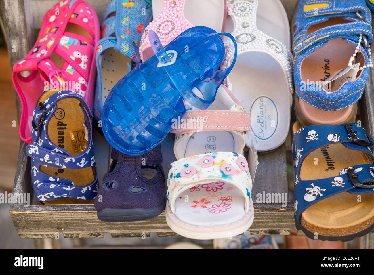 Sandalias multicolor para niños y calzado de verano a la venta en el casco antiguo de Finalborgo, Finale Ligure, Liguria, Italia Foto de stock