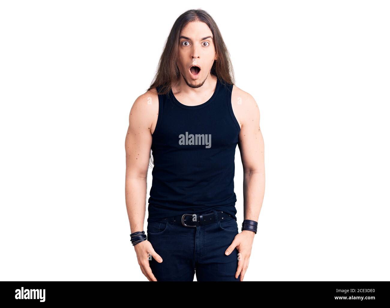 Joven hombre adulto con pelo largo con estilo goth con ropa negra miedo y  sorprendido con sorpresa y expresión asombrada, miedo y cara excitada  Fotografía de stock - Alamy