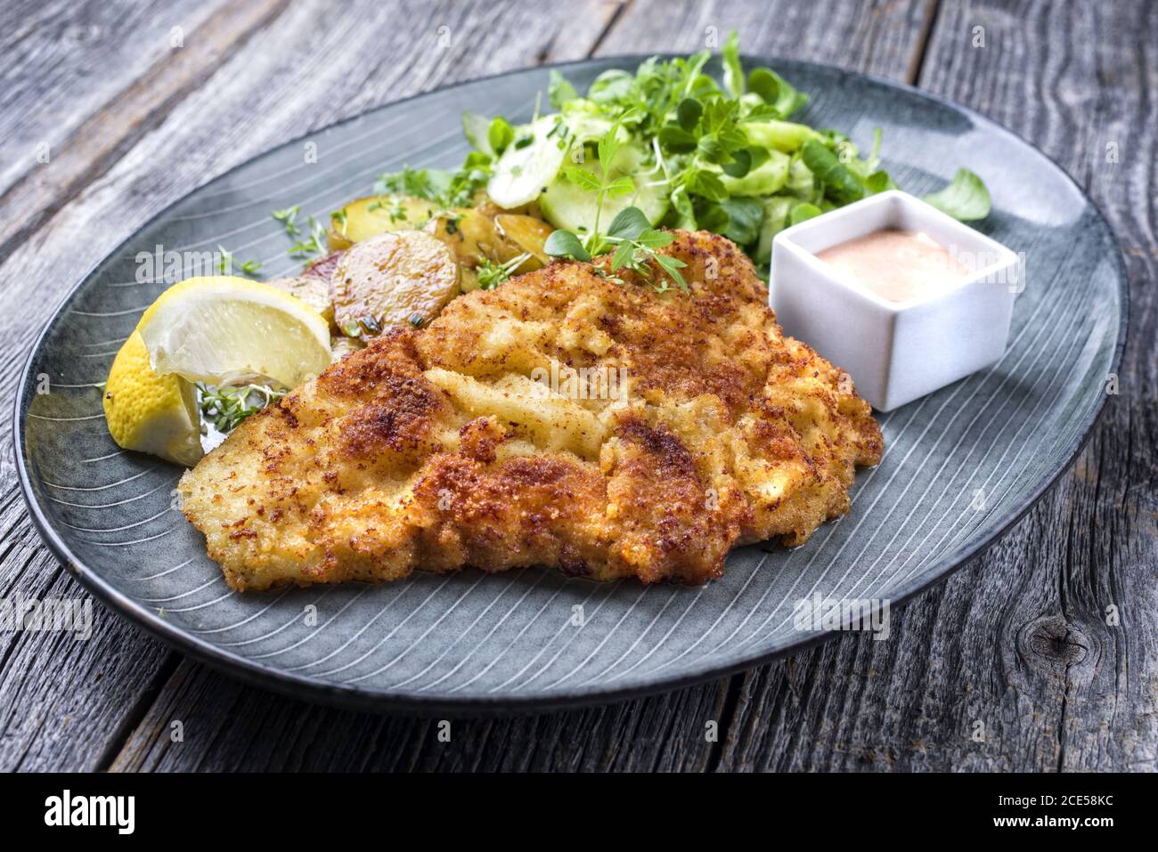Schnitzel de Wiener frito de ternera con patatas fritas y lechuga como placa de diseño moderno Foto de stock
