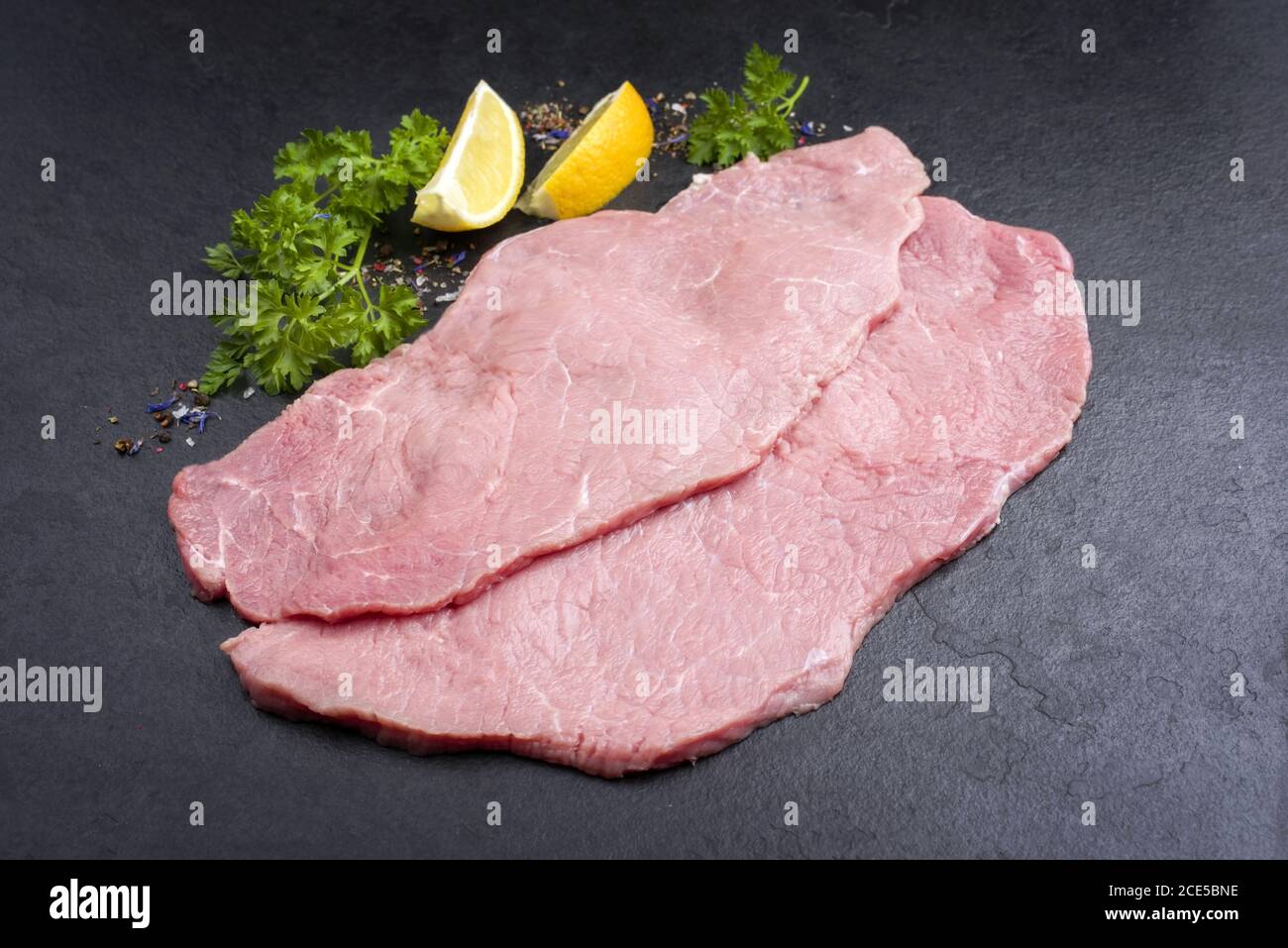 Schnitzel de ternera cruda de arriba como primer plano sobre fondo negro con espacio de copia Foto de stock