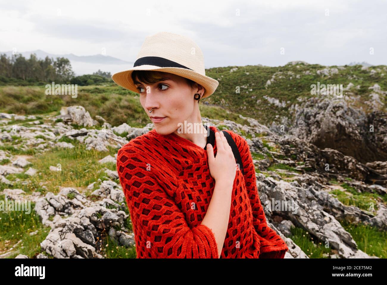 Mujer viajero en poncho de punto rojo y sombrero caminando Colina de hierba  mientras disfruta de vacaciones en Asturias en España Fotografía de stock -  Alamy