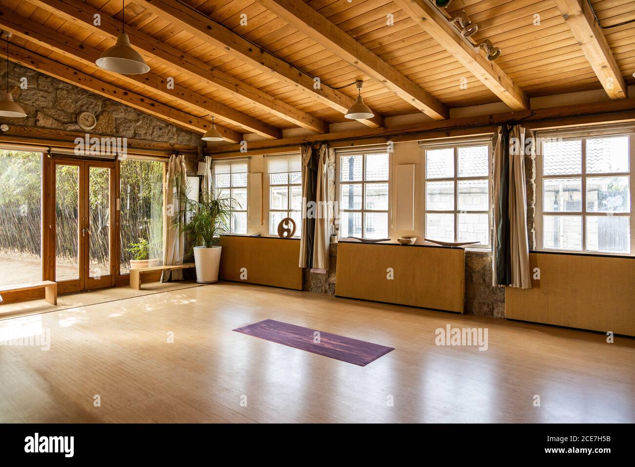Colchoneta de yoga colocada en el suelo de madera dentro de un espacioso pabellón decorado en estilo oriental situado en el país tropical Foto de stock