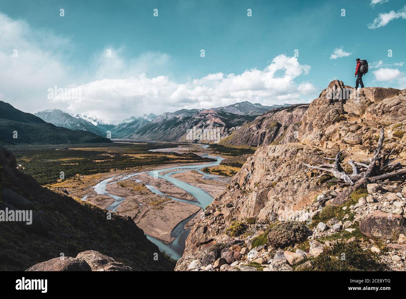 Excursionista en la cima de una montaña admirando un valle con un hermoso río en la Patagonia. Foto de stock