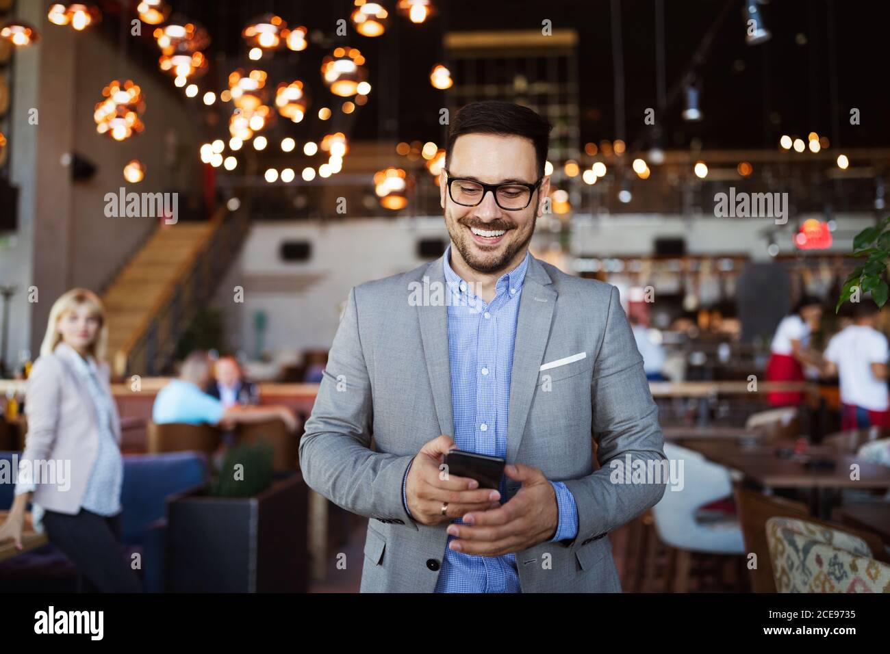 Apuesto hombre de negocios feliz recibir un mensaje en su teléfono celular Foto de stock