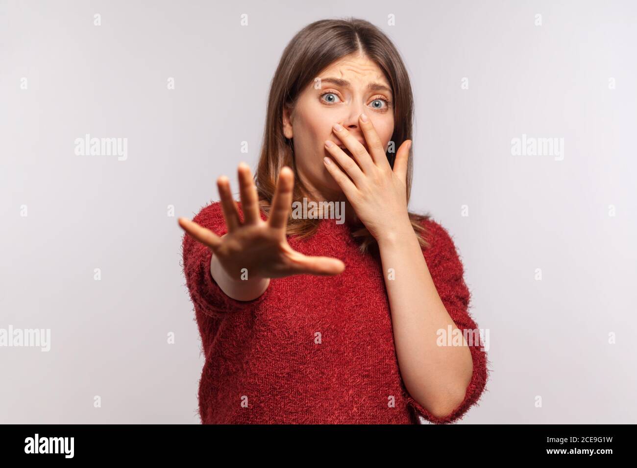 ¡no, me temo! Retrato de niña asustada en pánico en el suéter de shaggy gestuing detener y mirar sorprendido con los ojos asustados, cubriendo la boca no para sh Foto de stock
