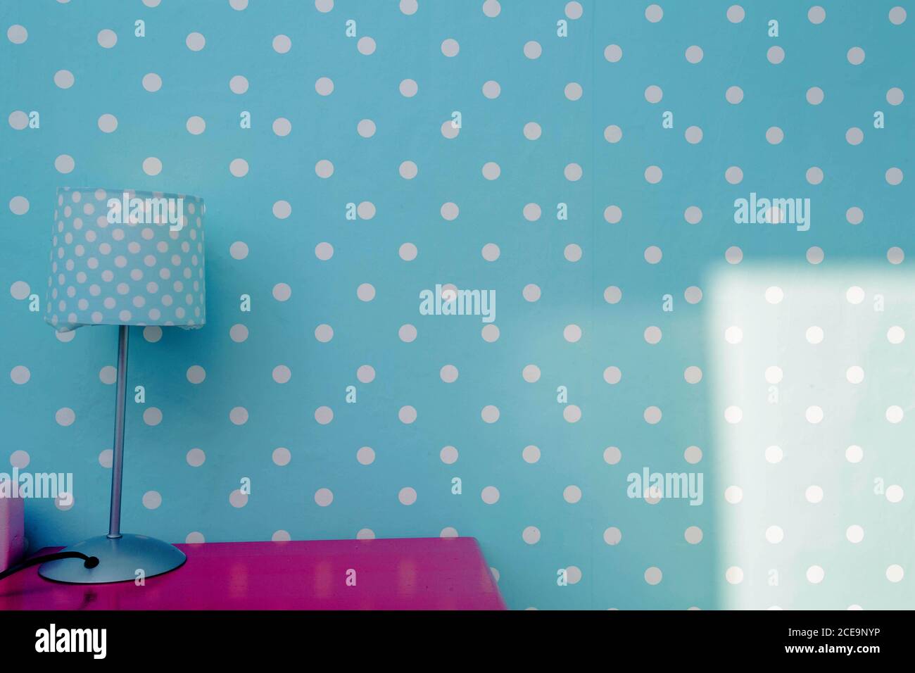 Lámpara de luz nocturna con pared azul y puntos blancos papel tapiz, colorida habitación para niño tabla rosa de diseño moderno. Foto de stock