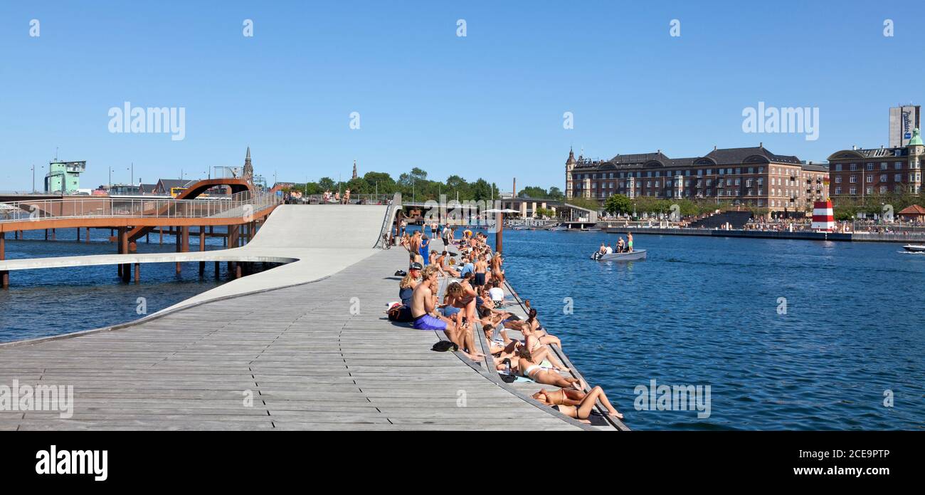Gente tomando sol en las olas de Kalvebod y las islas oficiales Brygge Baño del puerto en el lado opuesto del canal interior del puerto Copenhague en un día de verano Foto de stock