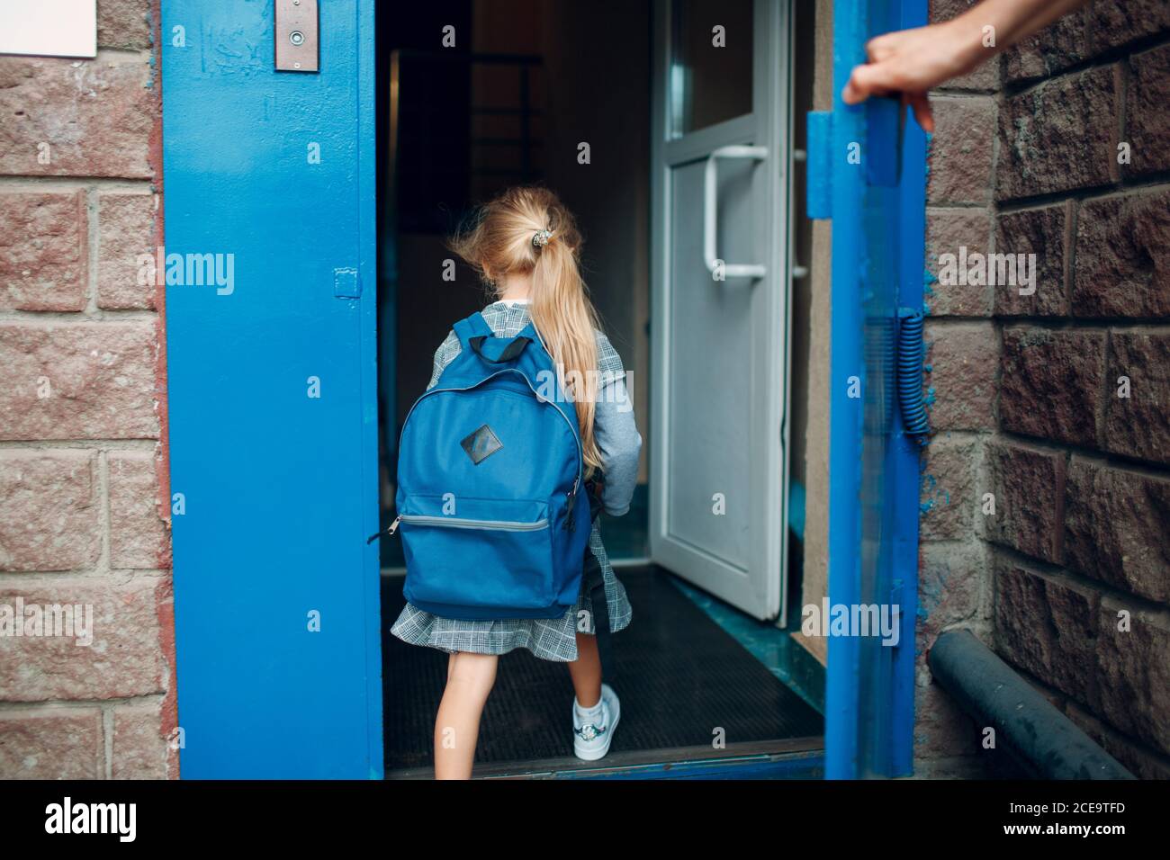 Vista trasera del padre vuelve a casa de la escuela con su hija cargando mochila Foto de stock