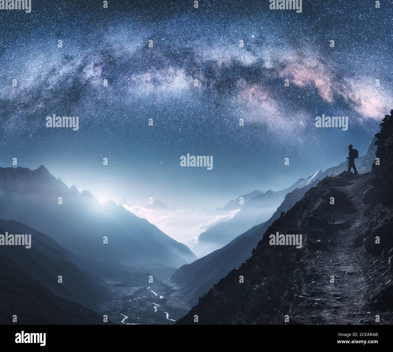 Vía Láctea arqueada, mujer y montañas por la noche Foto de stock