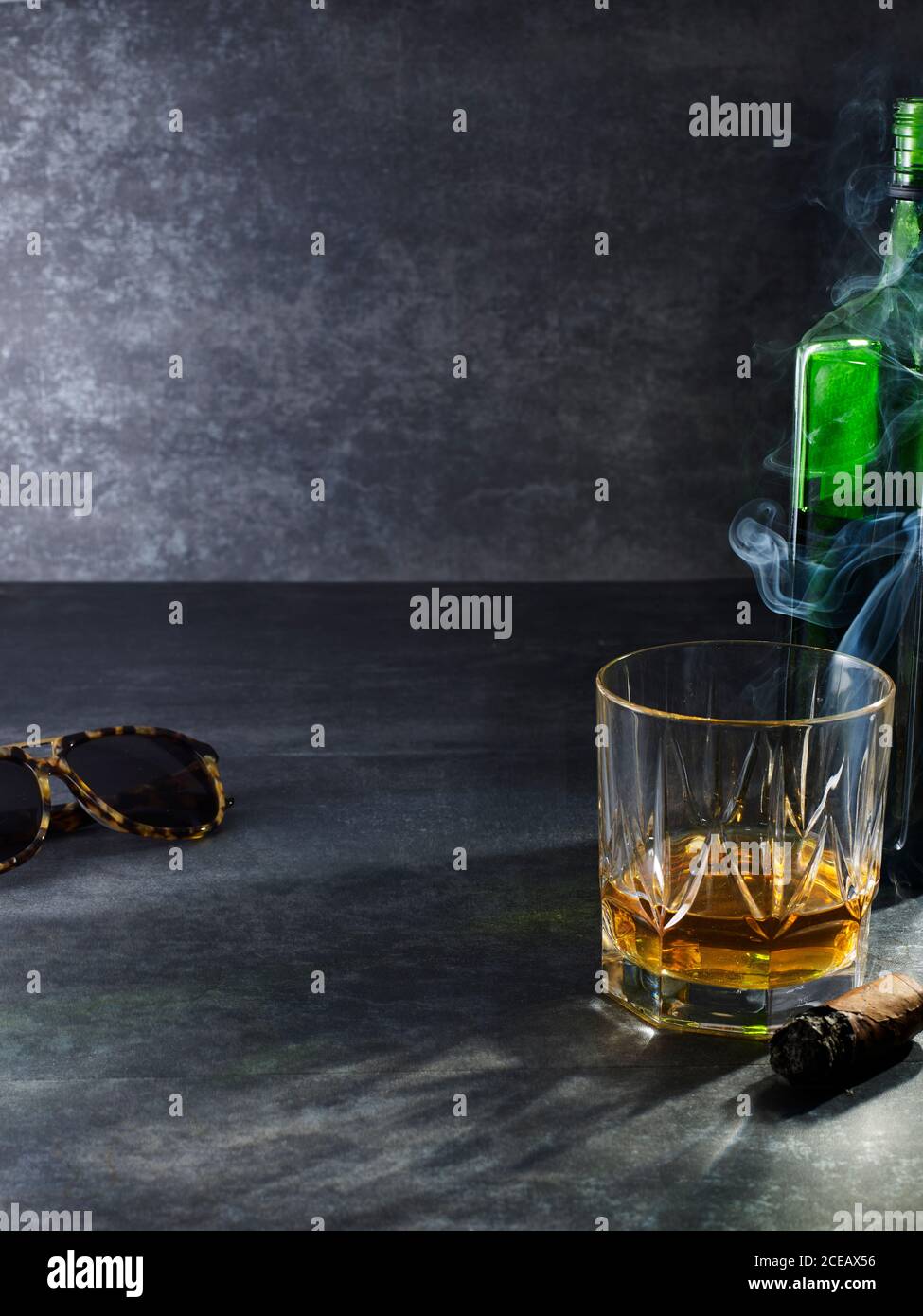 Composición de cristal con whisky dorado sobre fondo gris con gafas de sol  y cigarros para fumar Fotografía de stock - Alamy