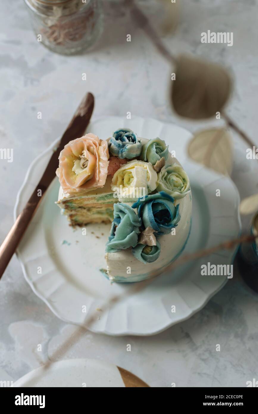 Porción de pastel de arco iris, relleno de crema de chantilly, y decorado  con flores de crema de mantequilla Fotografía de stock - Alamy