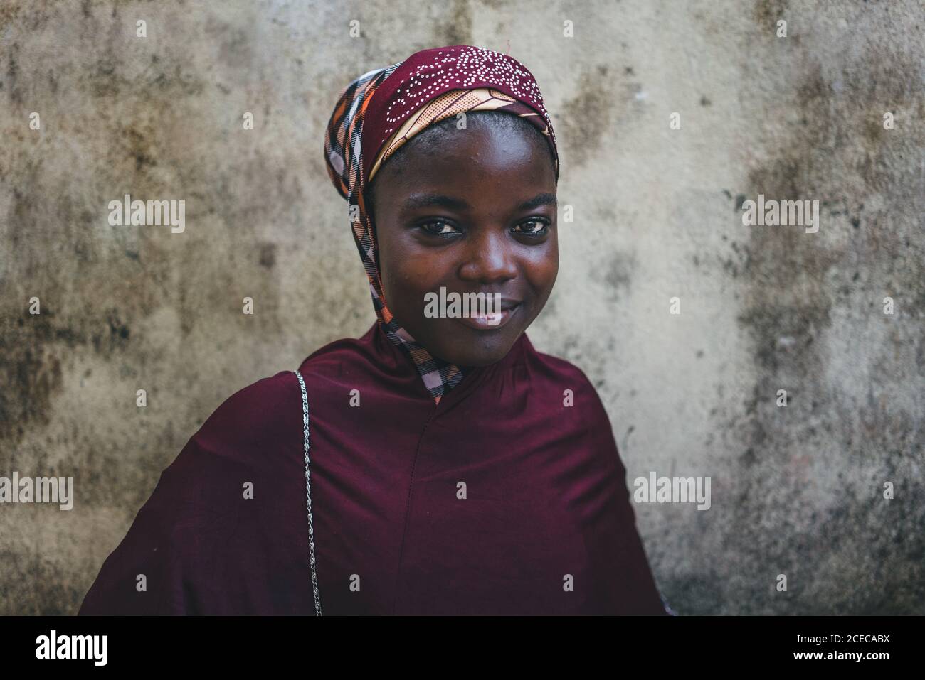 CAMERÚN - ÁFRICA - 5 DE ABRIL de 2018: Bonita mujer africana con ropa  tradicional roja, de pie en una pared áspera y mirando la cámara Fotografía  de stock - Alamy