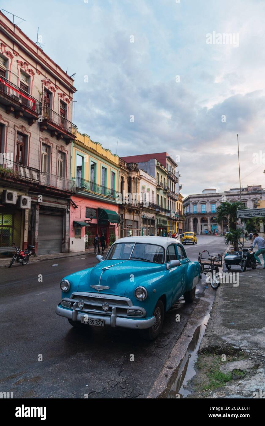 LA HABANA, CUBA - 6 DE NOVIEMBRE de 2018: Automóvil de época en la calle cerca de la construcción entre árboles y macho en día soleado en Cuba Foto de stock