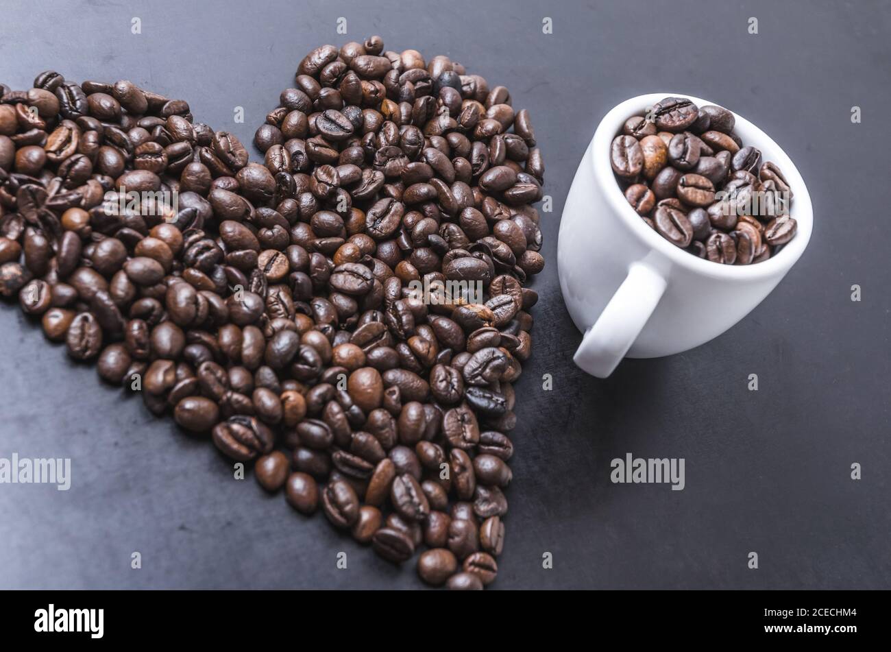 Granos de café con taza sobre fondo oscuro, en forma de corazón, primeros planos de vida, planos, estudio interior, me encanta el concepto de café Foto de stock