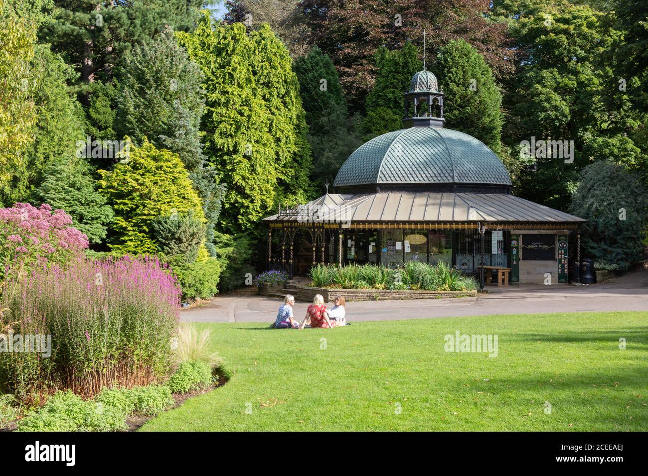 Tres mujeres sentadas frente al quiosco en el parque; Valley Gardens, en un soleado día de verano; Harrogate Yorkshire UK Foto de stock