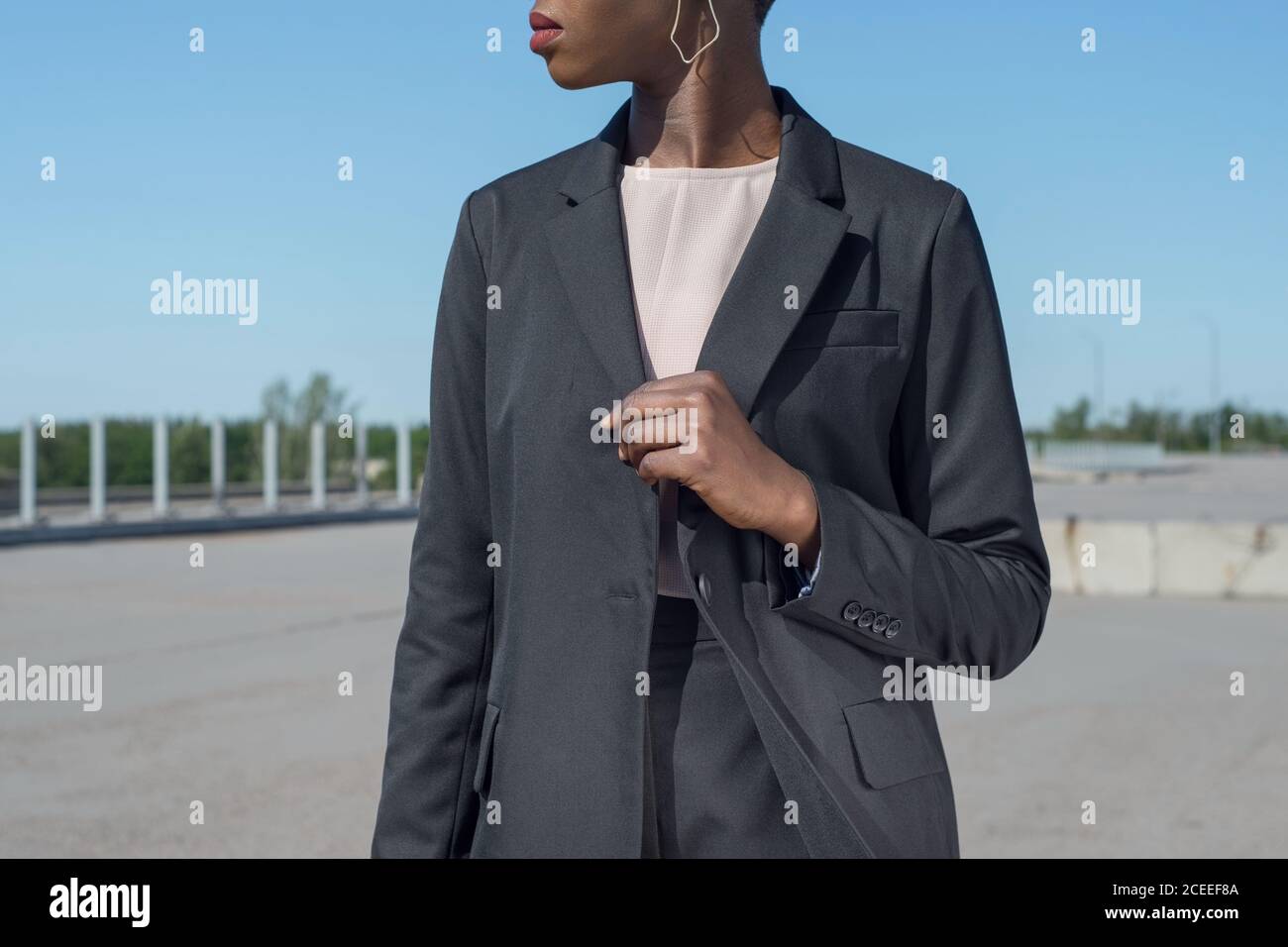 africana de moda mujer de negocios en una chaqueta y pantalón de traje negro de negocios posando mostrando los detalles un traje. Sobre el fondo azul Fotografía de stock
