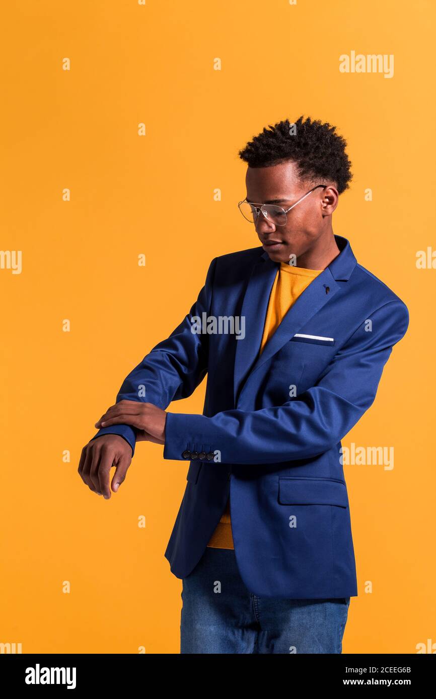 Joven hombre negro con estilo con chaqueta azul moderna con jeans y jumper  de pie sobre fondo naranja Fotografía de stock - Alamy