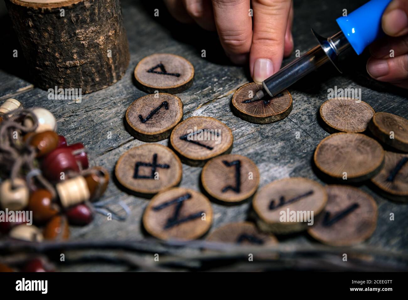 hombre escribiendo runas de madera con una pirografía o pokerwork, fondo esotérico Foto de stock