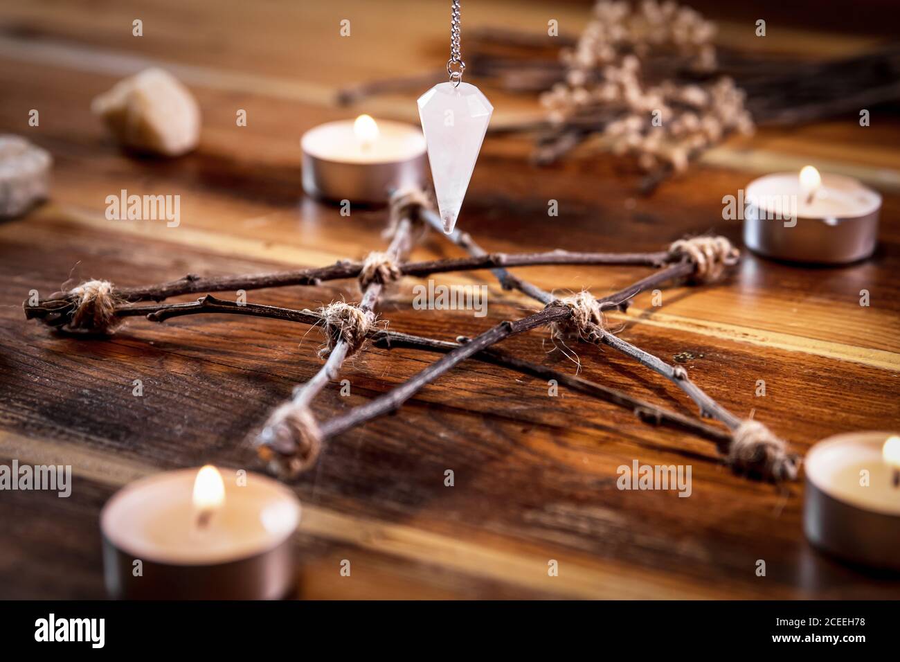 Pentagrama de madera y péndulo con velas, ocultismo y magia, closeup Foto de stock