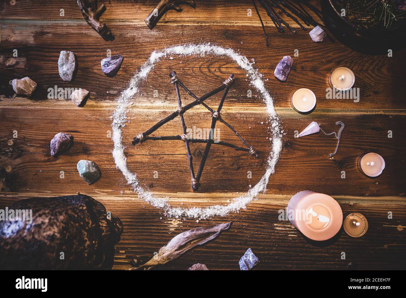 Ingredientes y materiales para un ritual occultly con un pentagrama o pentacle, piedras preciosas, un péndulo y un cráneo humano, flatlay Foto de stock