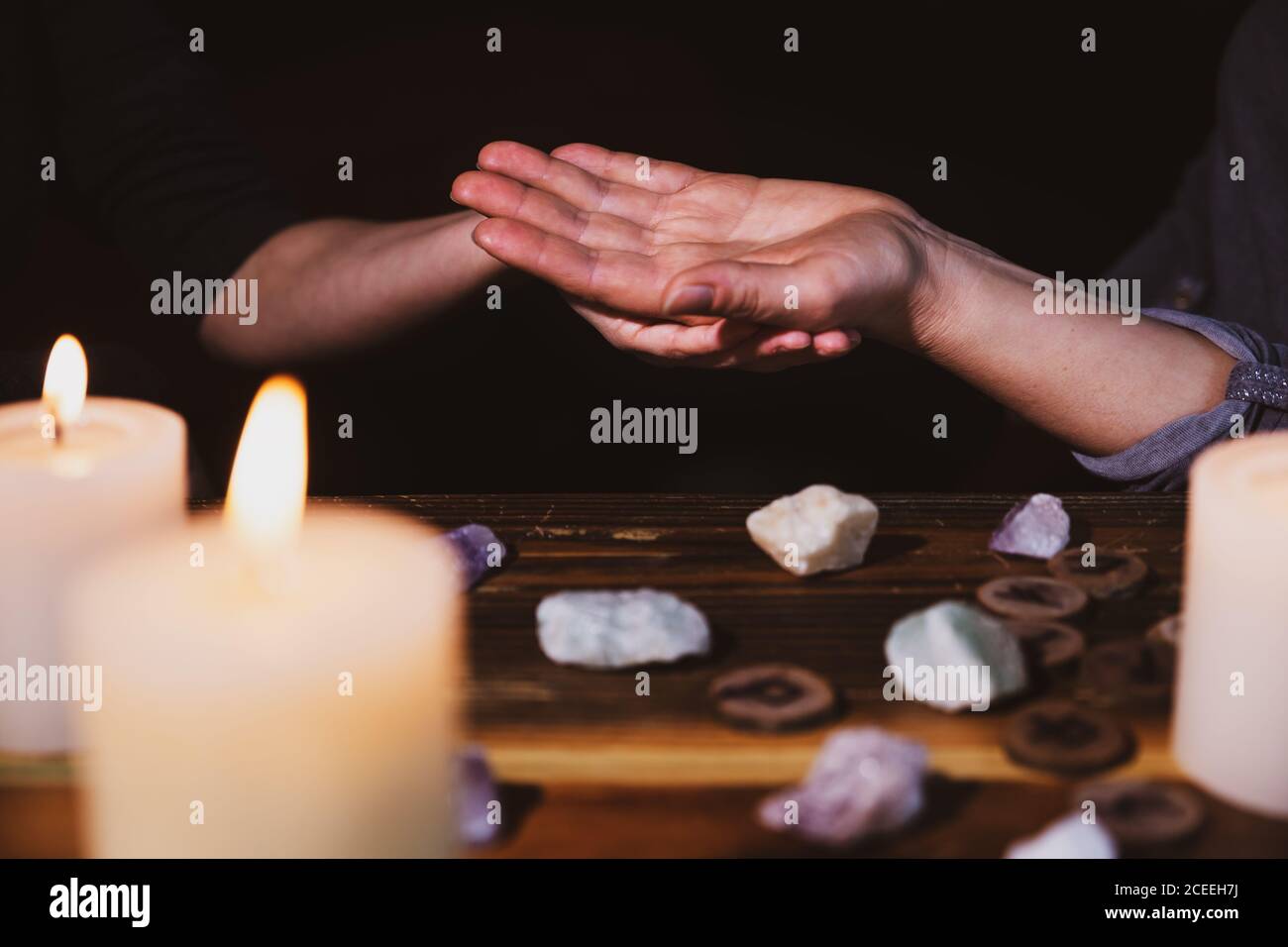 palmistry o lectura de la palma, fortuneteller sosteniendo una mano, piedras y velas curativas, horóscopo y oráculo Foto de stock