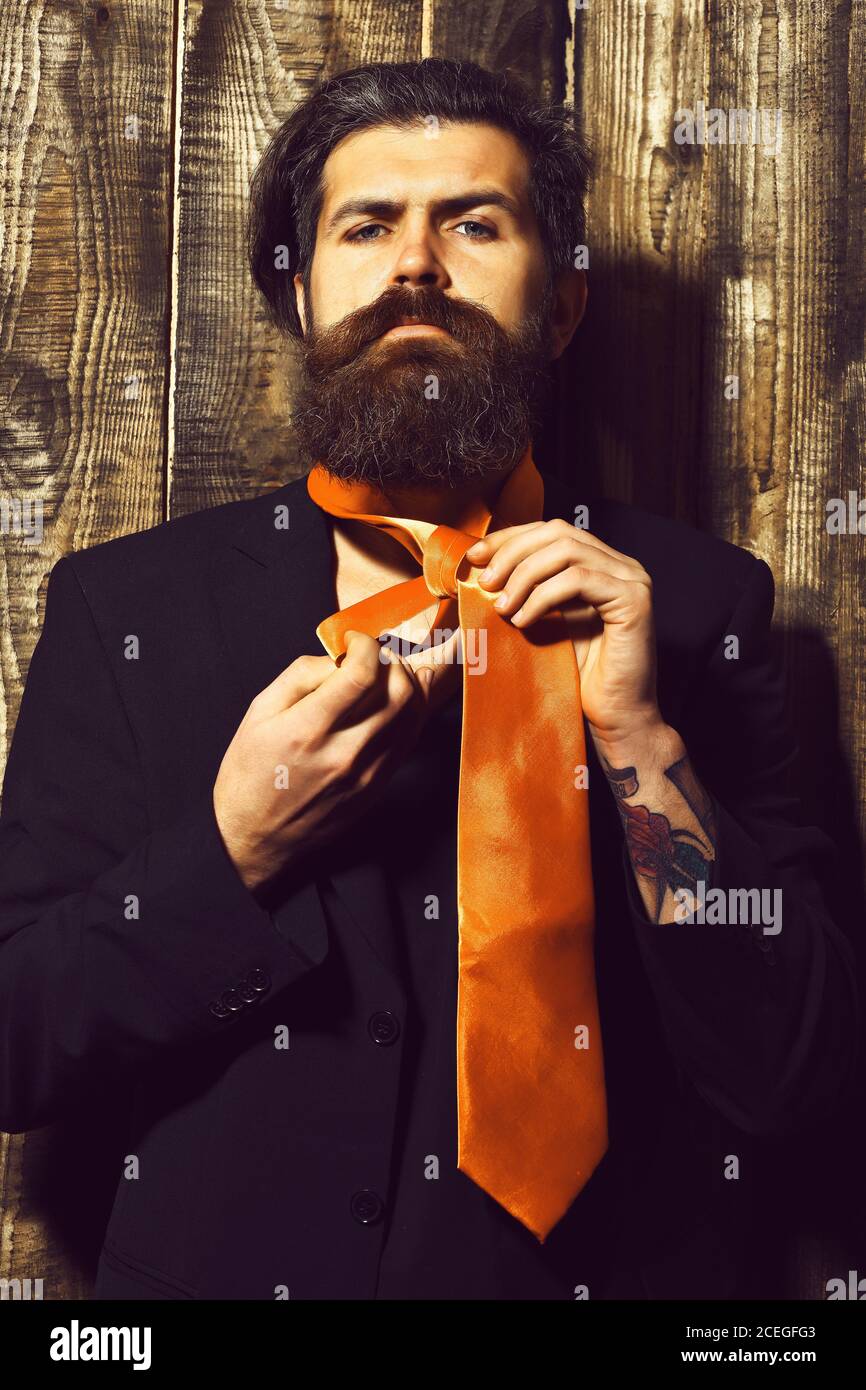 Hombre Barbado, barba larga. Brutal hipster caucásicos con bigote tienen  ácido en traje de corbata naranja sobre fondo marrón madera vintage studio  Fotografía de stock - Alamy