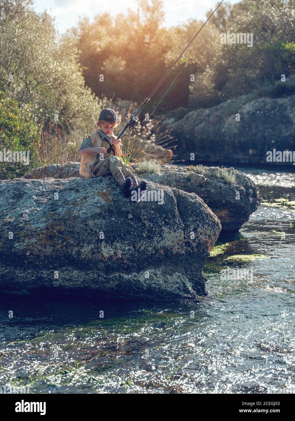 Niño sentado y pescando Foto de stock