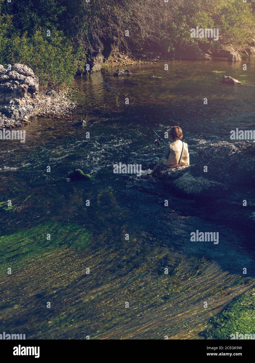 Niño sentado y pescando Foto de stock