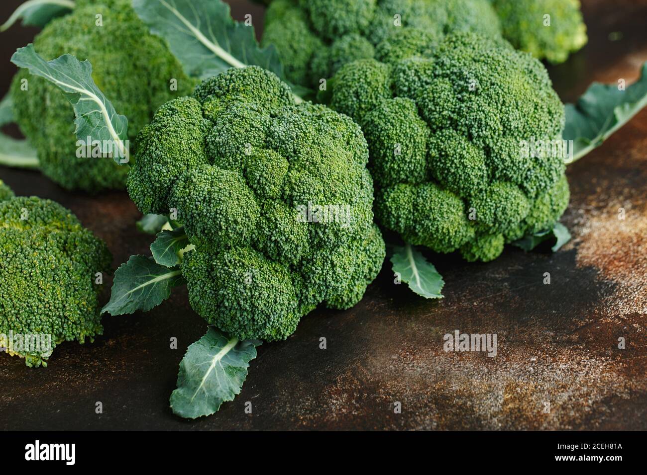 Brócoli verde fresco sobre un fondo marrón oscuro. Macro foto verde brócoli vegetal fresco. Verduras verdes para dieta y alimentación saludable. Foo orgánico Foto de stock