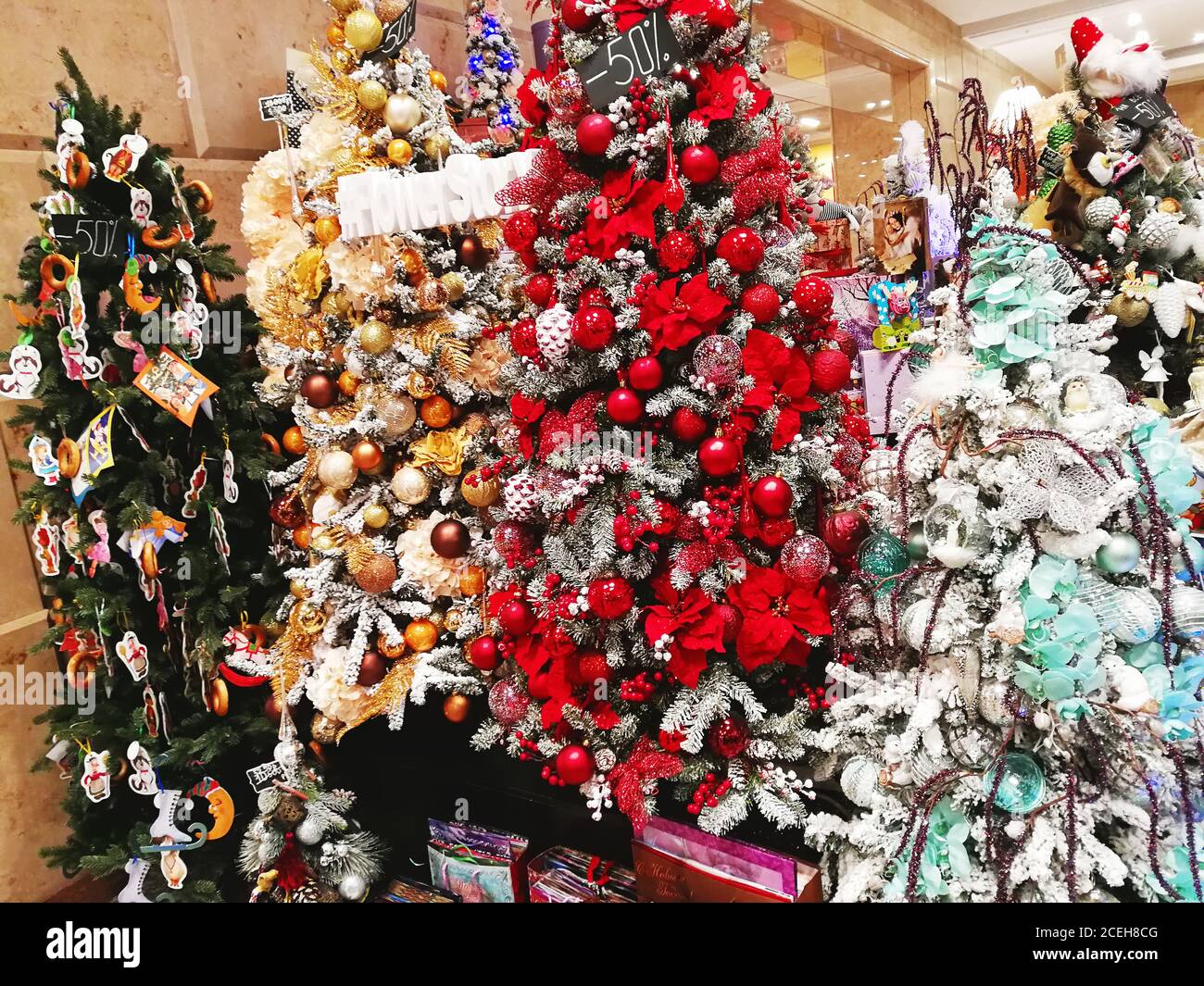 Árboles de Navidad multicolores decorados con bolas, flores y juguetes en  una ventana de tienda en un centro comercial Fotografía de stock - Alamy