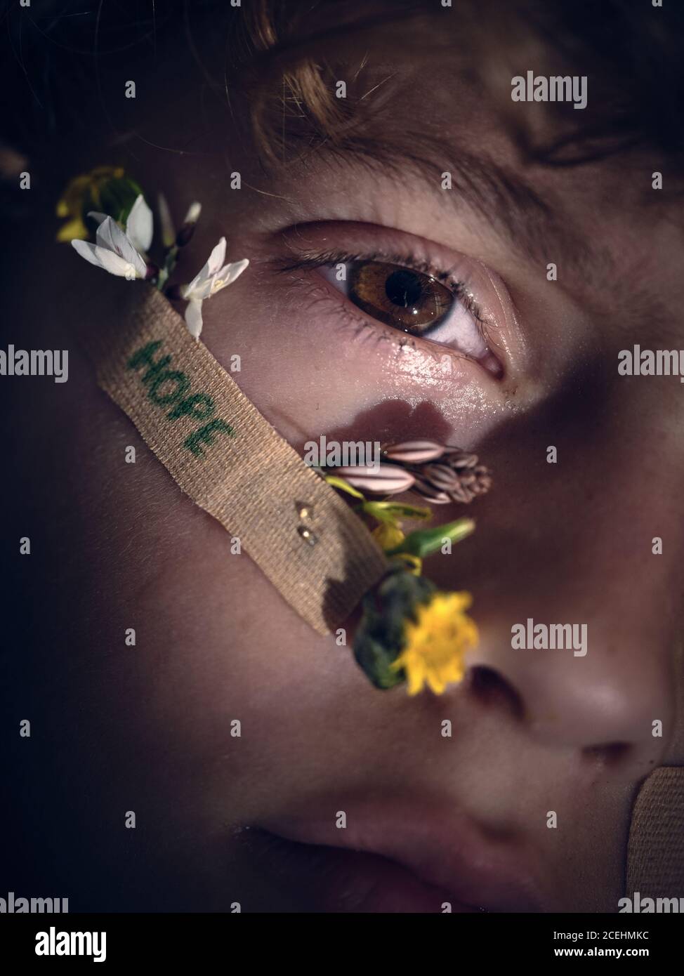 Concepto de closeup persona cara con ayuda banda con esperanza palabra y pequeñas flores frescas mirando la cámara en la oscuridad Foto de stock