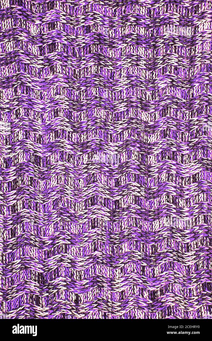 Bufanda de lana o suéter textura de primer plano. Fondo de punto ultra  violeta con un patrón de relieve. Trenzas en patrón de tejido de máquina  Fotografía de stock - Alamy