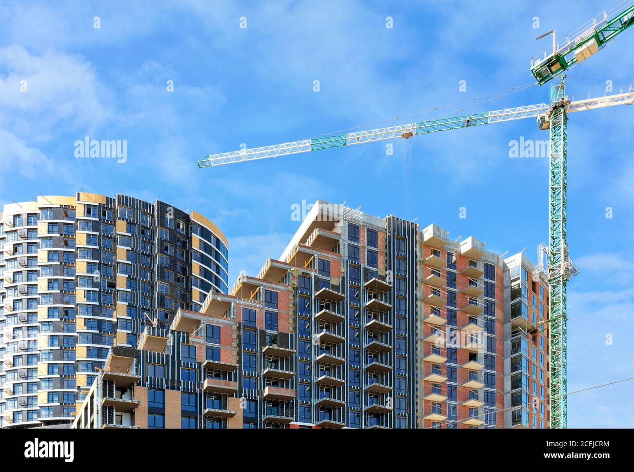 Sitio de construcción de un complejo residencial de varios pisos con pisos en cascada contra un cielo azul nublado, espacio de copia. Foto de stock