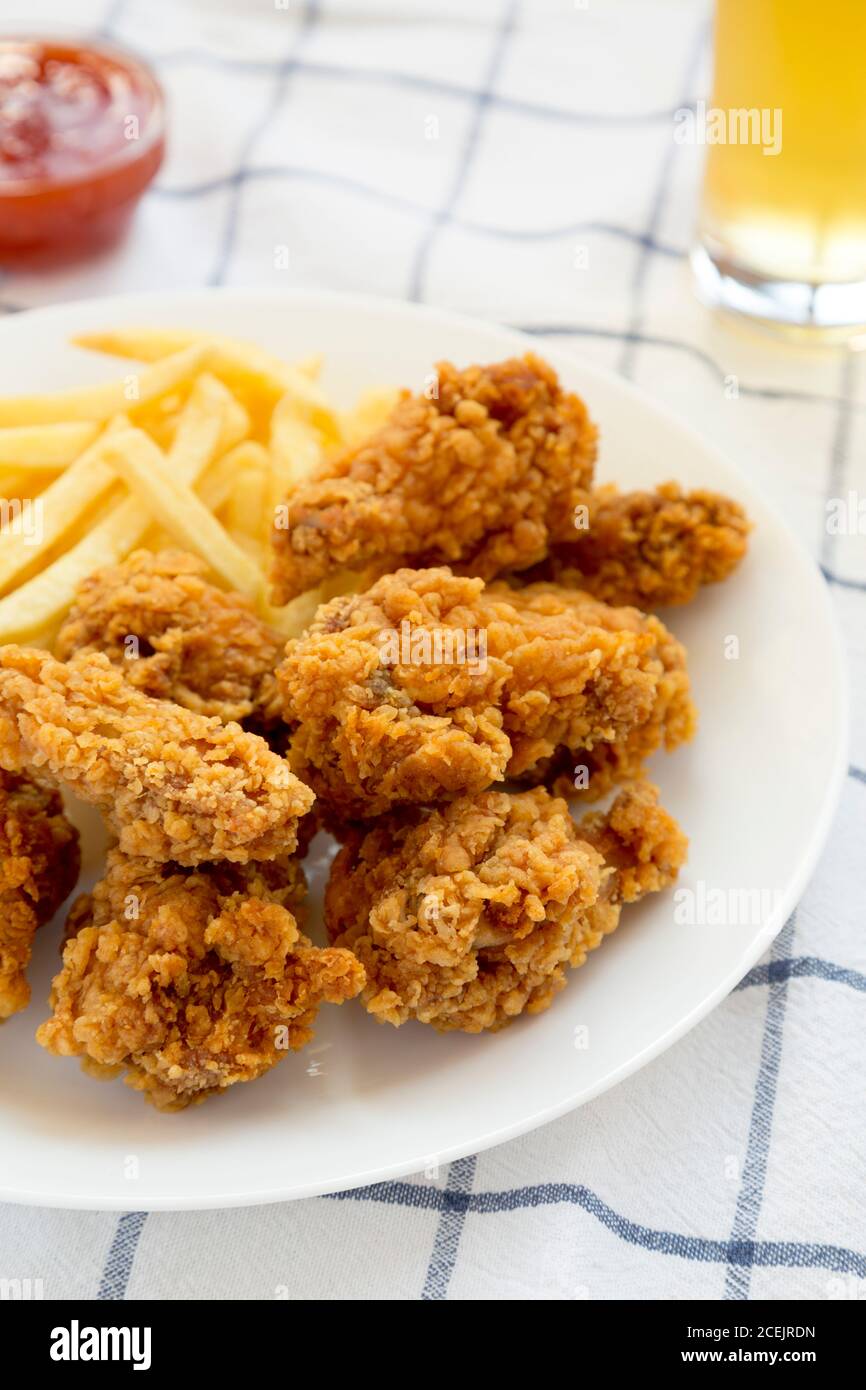 Alitas de pollo crujiente caseras y patatas fritas con salsa agridulce y un  vaso de cerveza fría sobre tela, vista en ángulo bajo Fotografía de stock -  Alamy