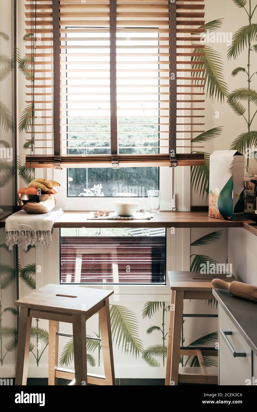 Dos taburetes y estante estrecho cerca de la ventana en la pequeña cocina  de elegante apartamento Fotografía de stock - Alamy