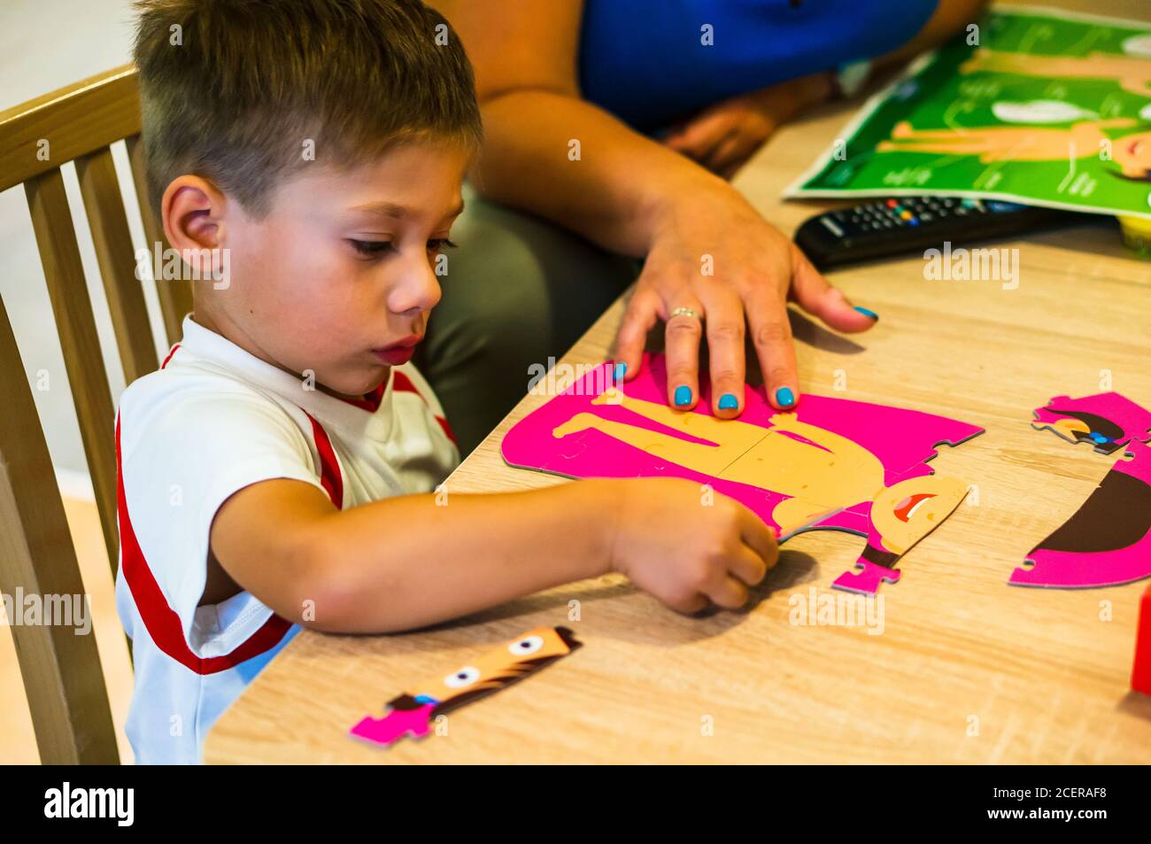 POZNAN, POLONIA - Aug 30, 2020: Niño pequeño resolviendo partes de rompecabezas de un humano por una mesa Fotografía de stock - Alamy
