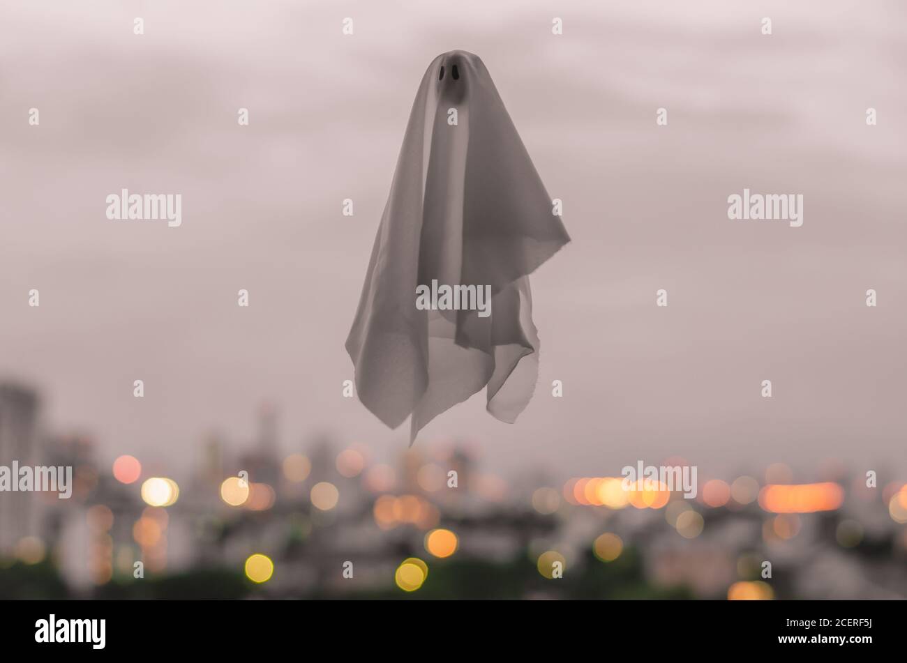 Hoja fantasma blanca volando en el cielo al atardecer con luces de la  ciudad de fondo. Halloween concepto de miedo Fotografía de stock - Alamy