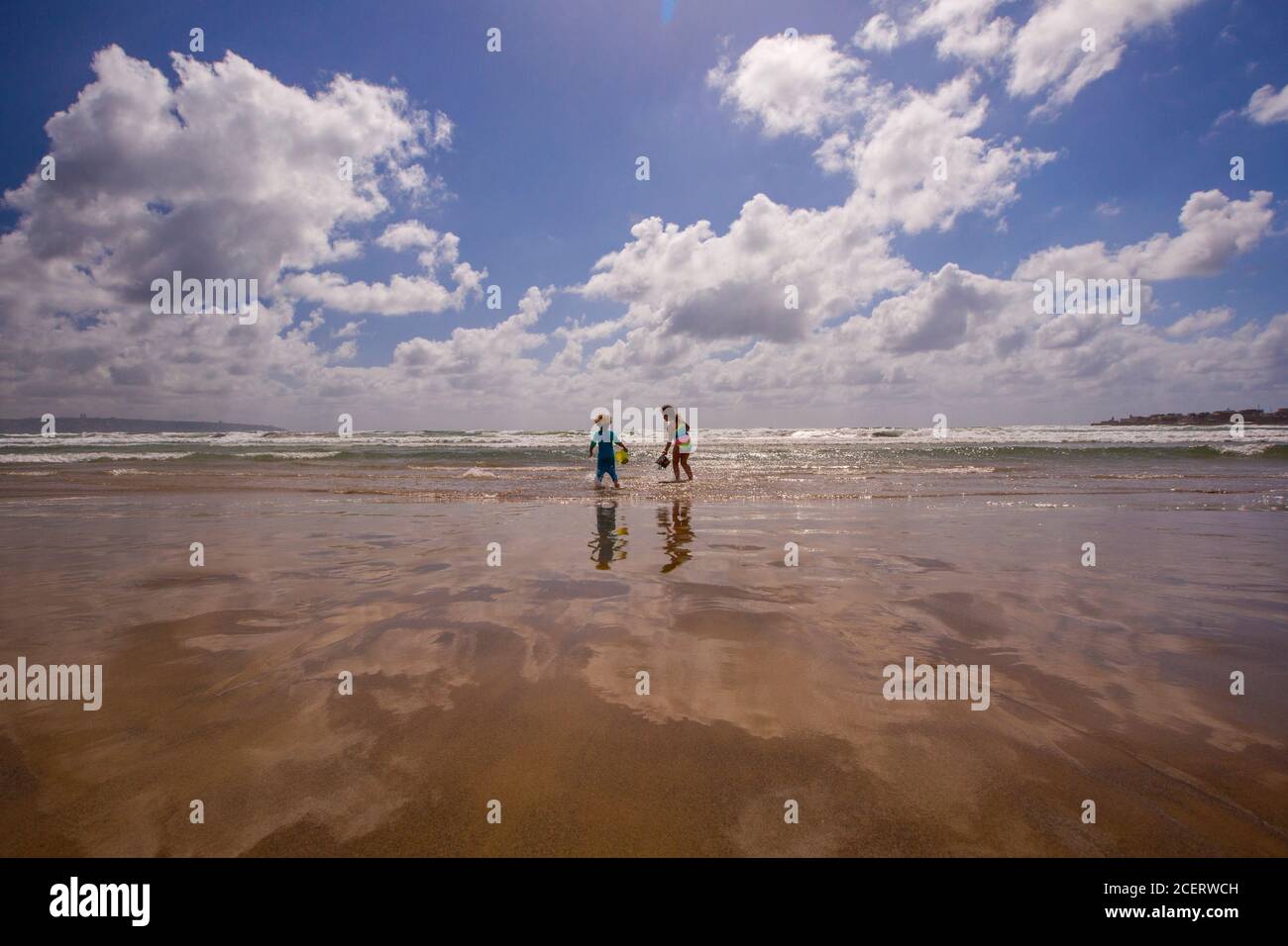 Los niños excitados exploran el banco de arena revelado por la marea baja En el Mar Mediterráneo Modelo de lanzamiento disponible Foto de stock