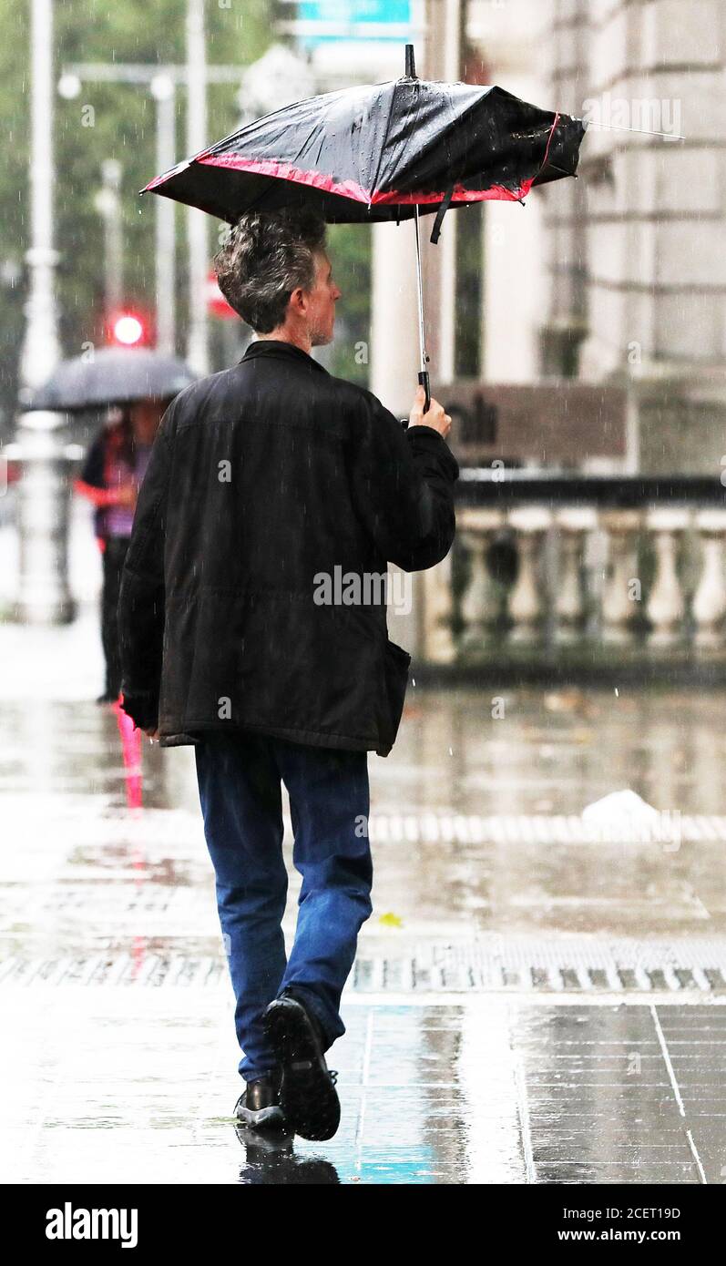 Un hombre usa un paraguas roto durante las duchas pesadas en el centro de  la ciudad de Dublín Fotografía de stock - Alamy