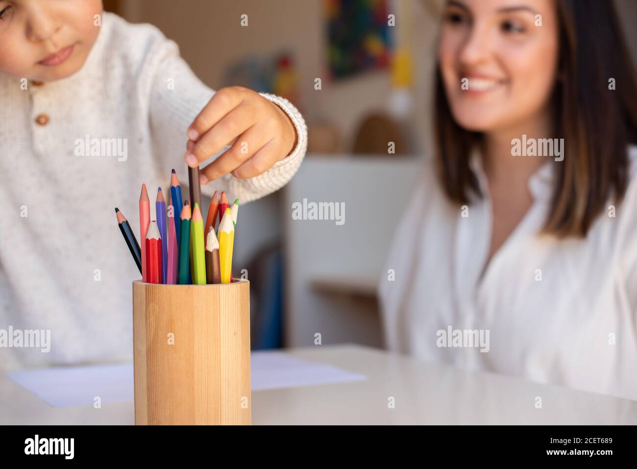 Pequeño niño de preescolar dibujo con lápices de colores con madre o maestro educador. Céntrese en los lápices. Homeschooling. Comunidad de aprendizaje. Montess Foto de stock