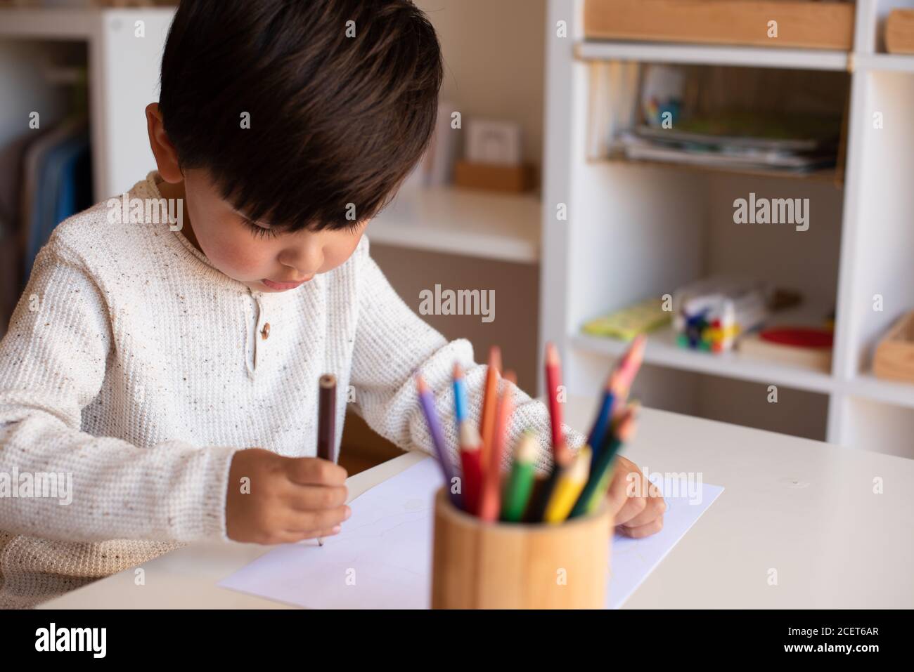 Pequeño niño de preescolar dibujo con lápices de colores. Homeschooling. Comunidad de aprendizaje. Escuela Montessori. Foto de stock