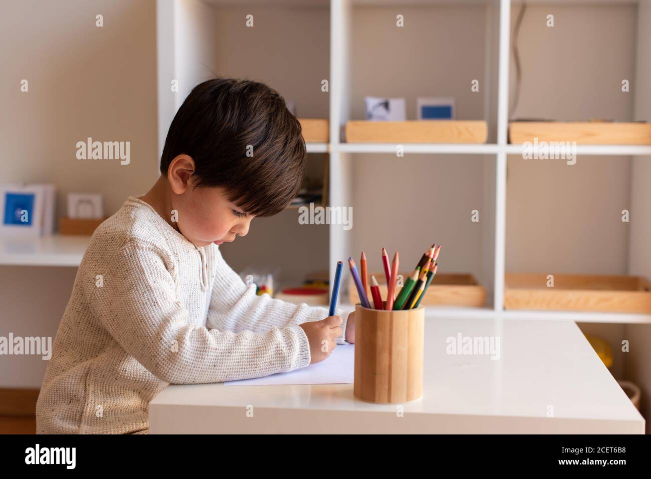 Pequeño niño de preescolar dibujo con lápices de colores. Homeschooling. Comunidad de aprendizaje. Escuela Montessori. Foto de stock