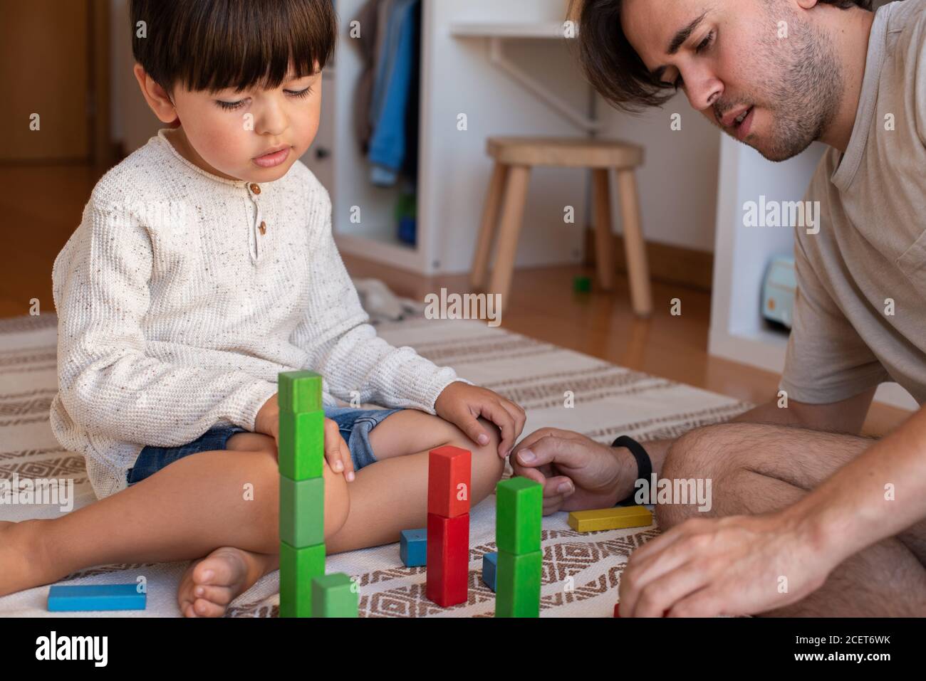 Niño pequeño y su padre jugando en casa con bloques de madera. Homeschooling. Quédate en casa. Tiempo en familia Foto de stock