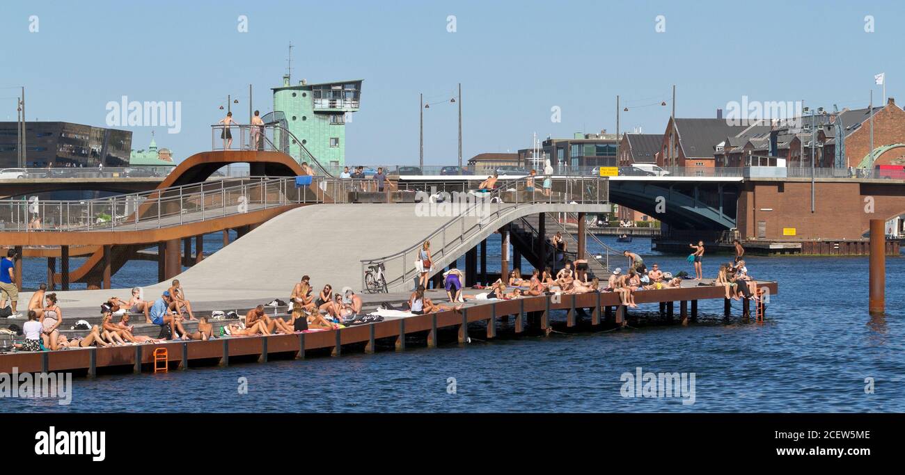 Kalvebod Bølge, Kalvebod olas en un cálido y soleado día de verano lleno de gente tomando el sol y bañándose. Puente Langebro en el fondo. Foto de stock
